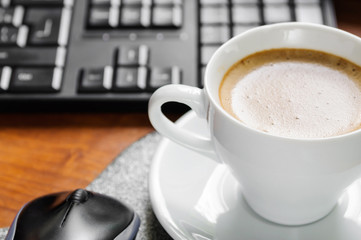 Coffee cappuccino, keyboard and mouse on the table
