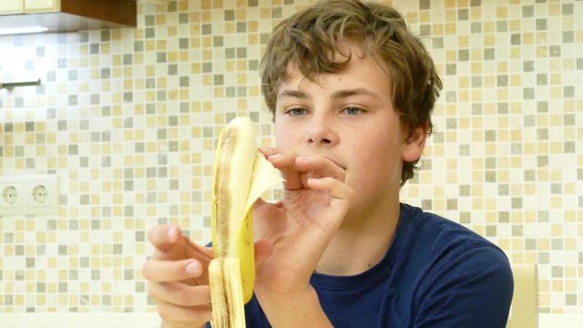 Young boy eating a banana with pleasure.