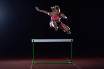 woman athlete jumping over a hurdles