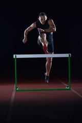 athlete jumping over a hurdles