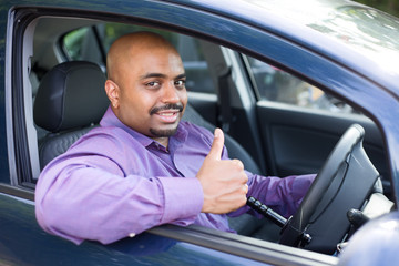 man with the thumbs up symbol in a car fitted with a spinning steering aid knob