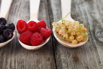 Different ripe berries in a wooden spoons