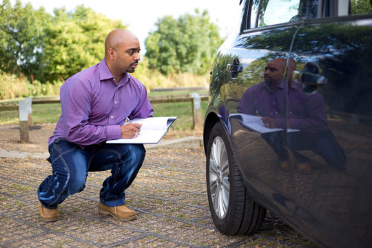 Man Inspecting The Side Of A Car