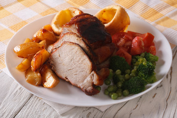 Sunday Roast: pork with vegetables and Yorkshire pudding closeup.
