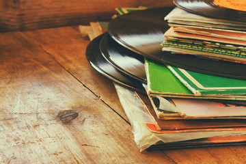 Obraz premium rekordy stosu z rekordem na górze nad drewnianym stołem. vintage filtrowane