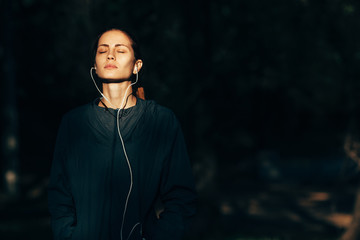 sporty woman wearing hood jacket and listening music