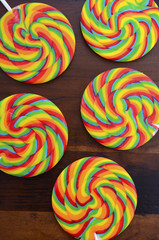 Fototapeta na wymiar Bright rainbow lollipop candy on dark wood table.
