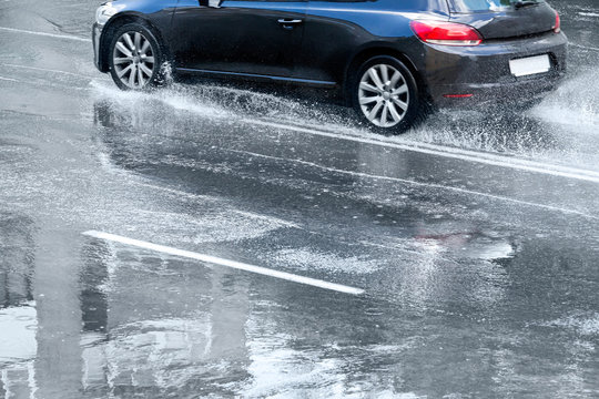 blue car splashes on flooded road