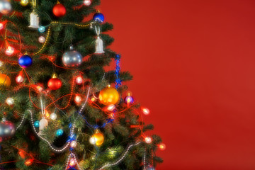 Fototapeta na wymiar Multicolour Christmas tree with decorations and lights and red background