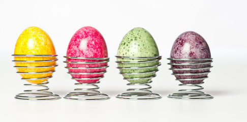 Multicolor hand painted easter eggs in metal holders on white background