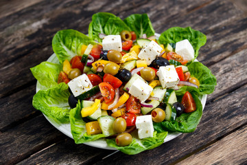 Fresh  Vegetable Greek Salad with Feta cheese, black and green olives, olives oil, cherry tomatoes, yellow pepper, red onion, cucumber. On wooden table.