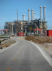 Fototapeta premium road leading to massive industrial factory with smokestacks