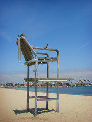 lifeguard chair on beach sand with water in background