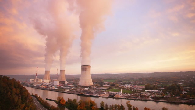 Time lapse sequence of a large nuclear power station at a river during sunset