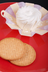 cream cheese in an environmentally friendly packaging made of wood with a round pastry on the red plate, top view, side view,