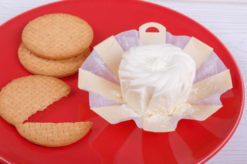 cream cheese in an environmentally friendly packaging made of wood with a round pastry on the red plate, top view, side view,
