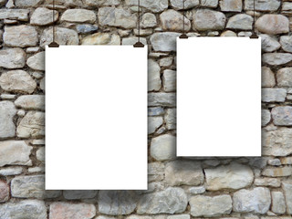 Two asymmetrical paper sheets with clips on ancient stone wall background