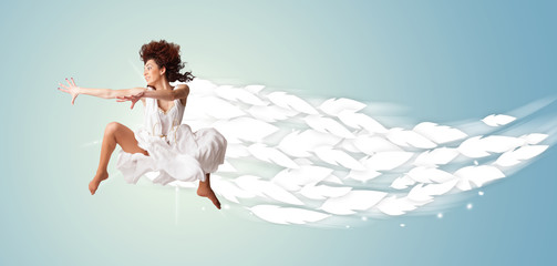 Healthy young woman jumping with feathers around her