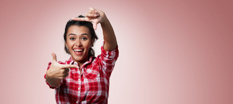 Gesturing finger frame. Portrait of handsome beautiful young mixed race woman looking at camera and gesturing finger frame while standing against isolated background.