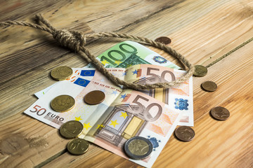Hangman's noose with money on brown wooden background