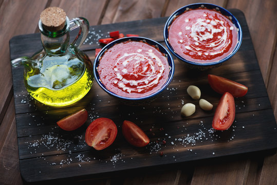 Ceramic bowls with gazpacho on a rustic wooden cutting board