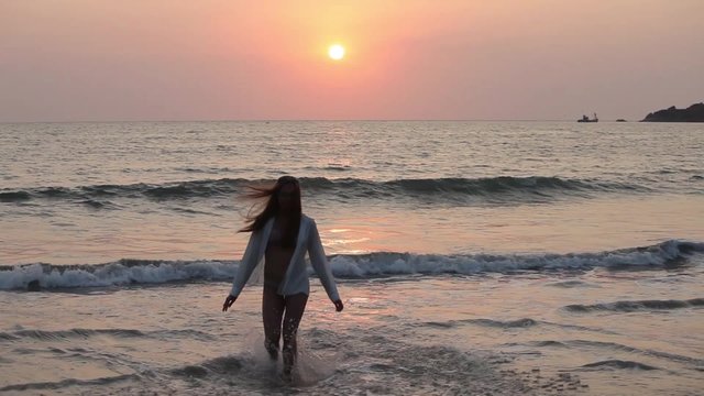 Young woman jumping on the beach on sunset.