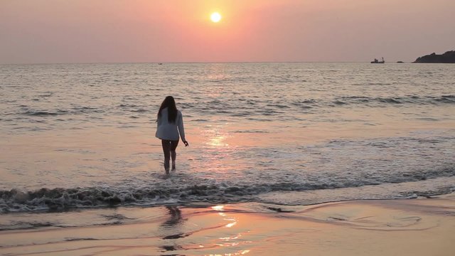 Young woman jumping on the beach on sunset.