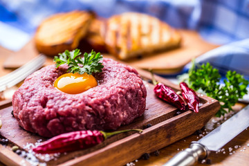 Raw beef .Tasty Steak tartare. Classic steak tartare on wooden board. Ingredients: Raw beef meat salt pepper egg garlic chilli herb decoration and toast bread