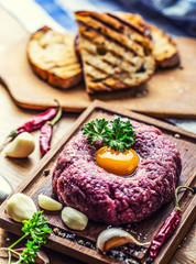 Raw beef .Tasty Steak tartare. Classic steak tartare on wooden board. Ingredients: Raw beef meat salt pepper egg garlic chilli herb decoration and toast bread
