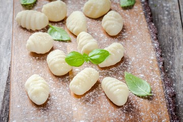 Fototapeta na wymiar homemade raw gnocchi with flour and fresh basil closeup