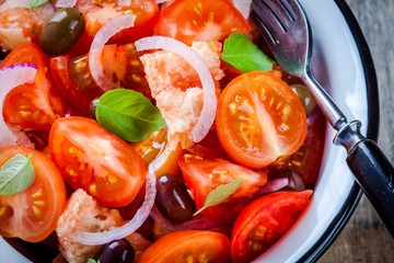 panzanella: Italian salad with tomatoes, ciabatta, olives, red onion and basil closeup