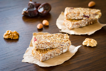 Granola bar or energy bar with oats, dates and nuts on brown wooden background