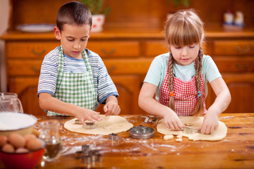 Two beautiful caucasian child making a cake, smiling happily,