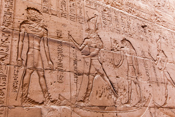 Fototapeta na wymiar Egyptian hieroglyphics on the stone wall. Ancient stone carved E