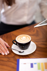 hands of a young woman in a cafe with coffee and digital tablet