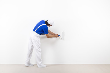 Painter with paintroller on white wall © guerrieroale