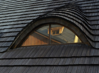 Traditional roof covered with shingles with window in an attic 