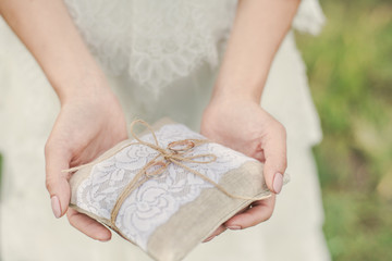 The bride is holding a pillow with the wedding rings