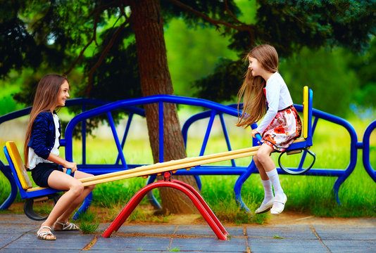 cute girls having fun on seesaw at playground
