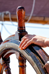 Fototapeta premium Ship wheel made of wood and brass on a sailboat at sea. Close up with copy space. Concept for leadership, navigation, staying the course.
