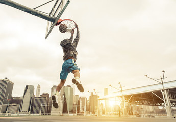 Basketball street player making a rear slam dunk. New york and Manhattan buildings in the background - obrazy, fototapety, plakaty