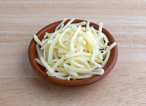 Portion of natural white mild cheddar cheese in bowl