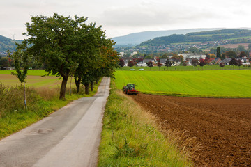 Fototapeta na wymiar An agricultural landscape with a tractor plowing the soil.