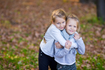 Fototapeta premium Little adorable sisters at warm sunny autumn day outdoors