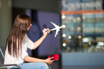 Happy young woman with air ticket and passports at airport