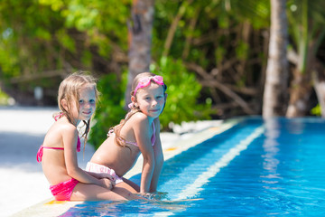 Fototapeta na wymiar Adorable little girls in outdoor swimming pool on vacation