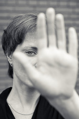 A woman in a very depressed mood covers his face, near a brick wall.
