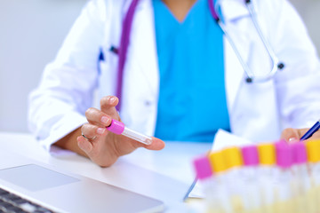 Woman researcher is surrounded by medical vials and flasks