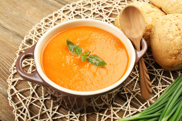 Carrot cream-soup with buns on table close up