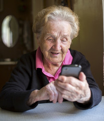 Elderly woman typing on the smartphone. Grandma.